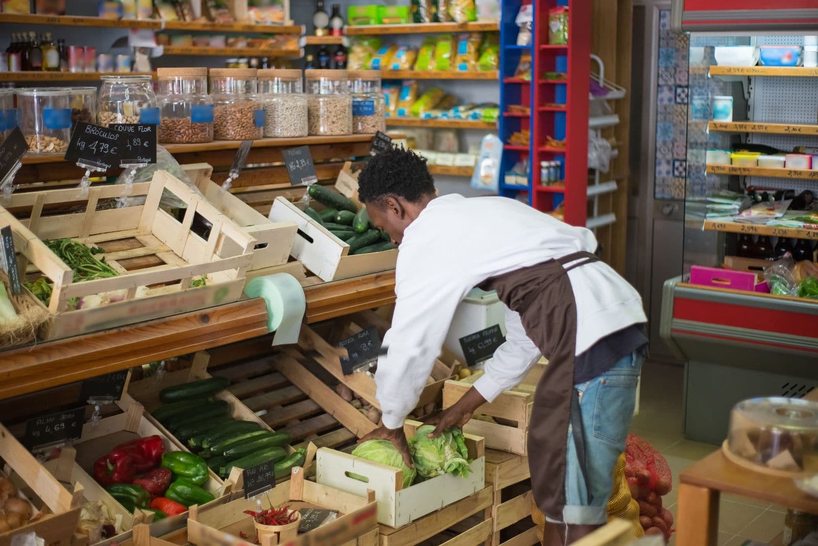 Profesional acomodando verduras en un puesto de frutas y verduras