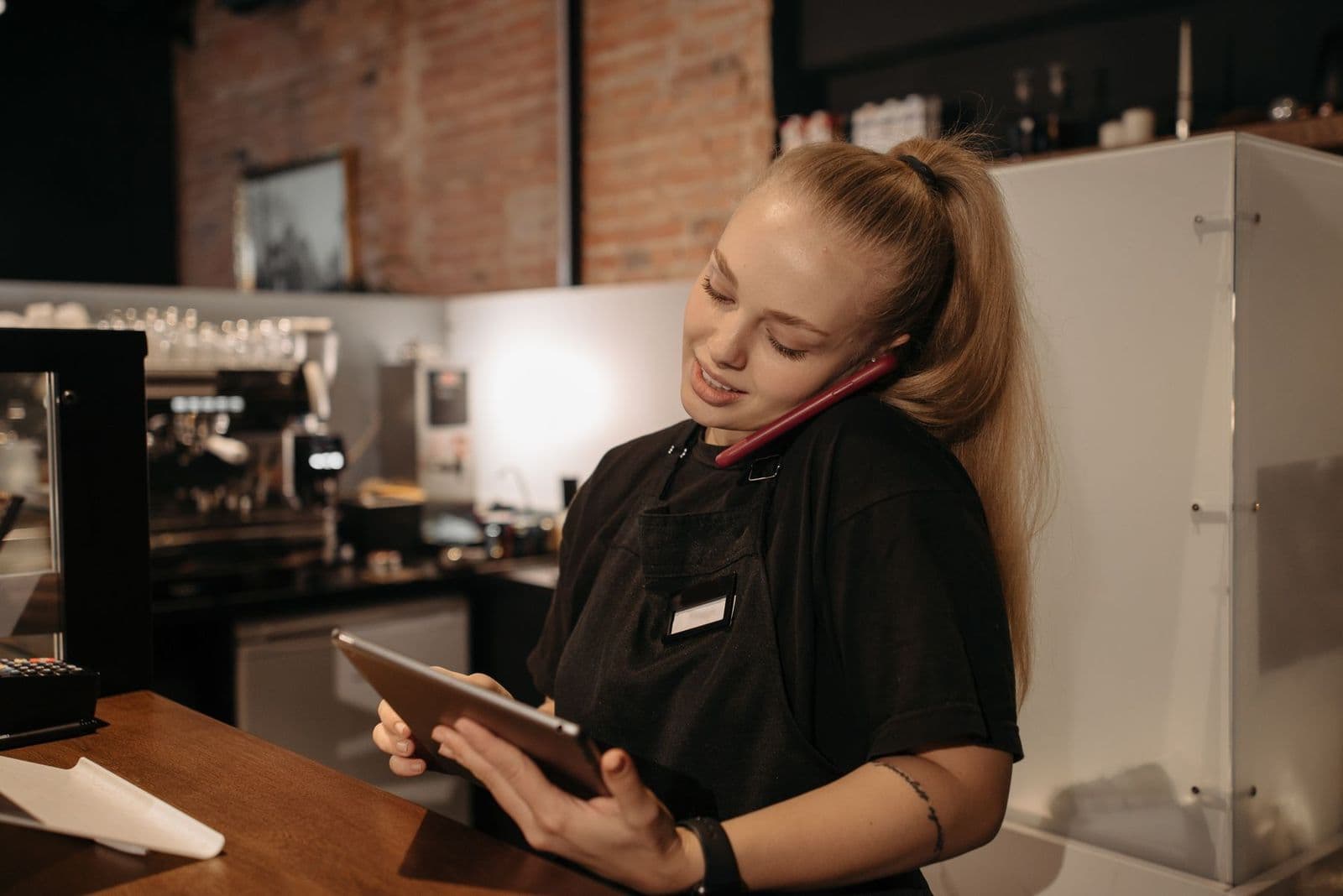 Dona de um café no balcão, com o tablet e o celular