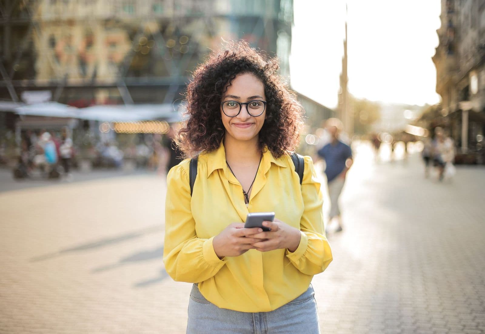 Profesional sonriendo al celular, en la calle